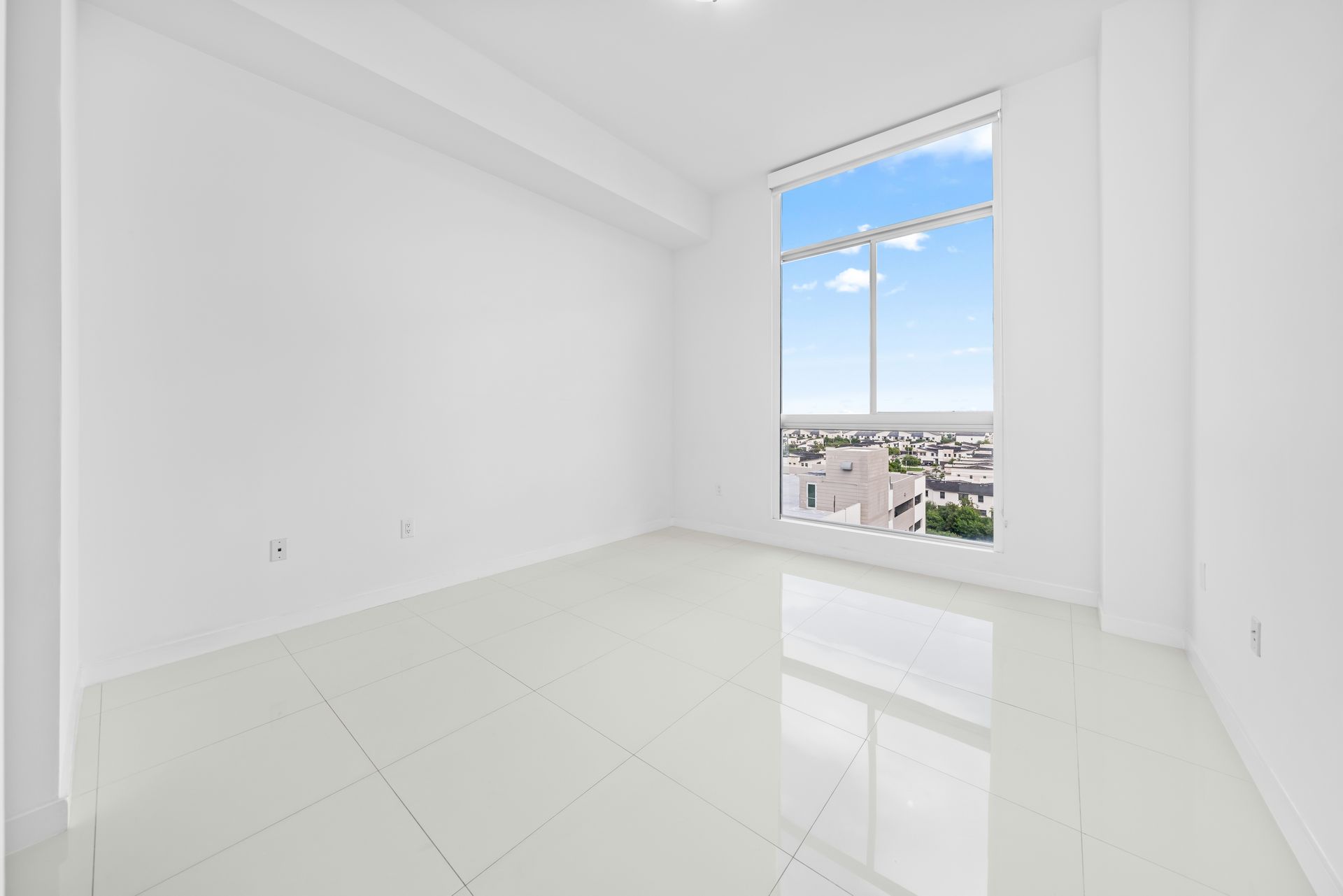 Empty white room with a large window overlooking city
